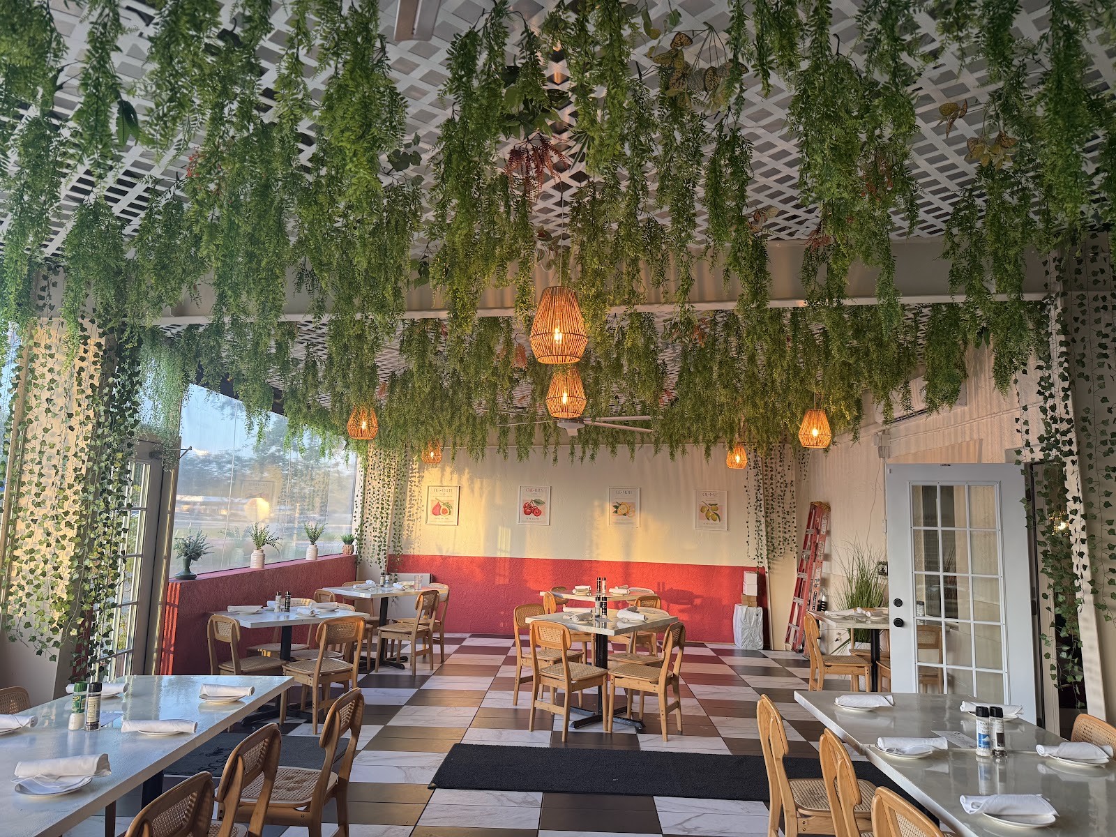 Scarpino's dining room with cascading green ivy across the ceiling, warm pendant lights, terracotta walls and a black-and-white checkerboard floor