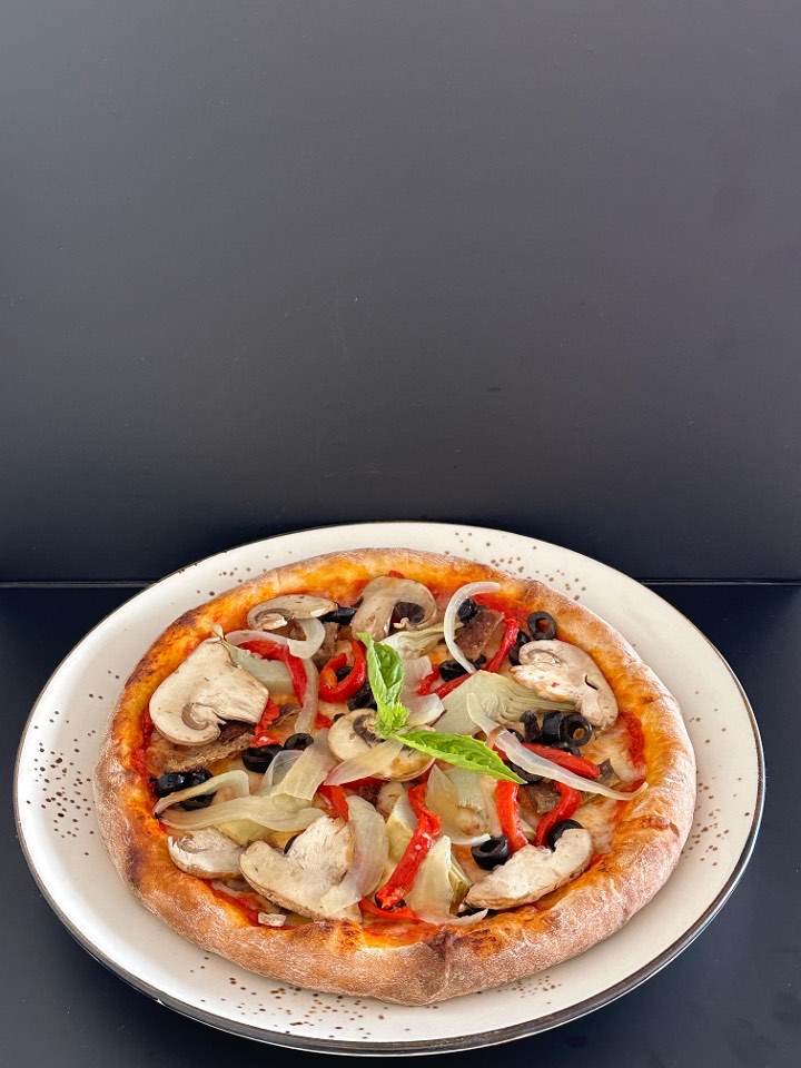 Wood-fired pizza with mushrooms, olives, peppers, onions and fresh basil